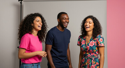 A group of three friends laugh out loud in a studio room, sharing kindness