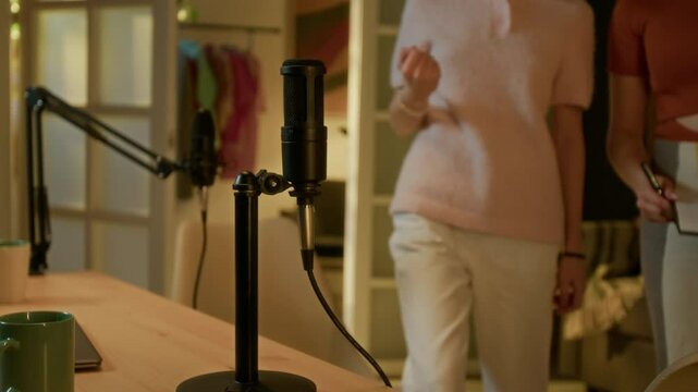 Two teen girl entering room while chatting, they adjusting microphones and checking it before podcast