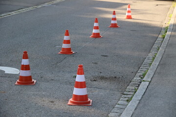 A row of orange and white traffic cones are lined up on a street