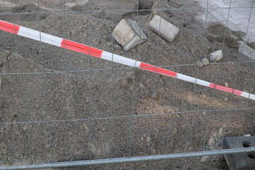 A red and white striped fence is in front of a pile of rubble