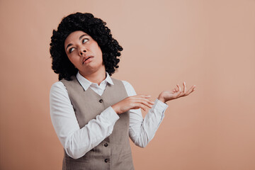 Confident young businesswoman with curly hair makes a dismissive gesture with an expression against...
