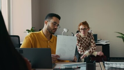 Medium shot of frustrated accountant discussing financial paperwork with male colleague in modern office, working on laptop, preparing monthly report - Powered by Adobe