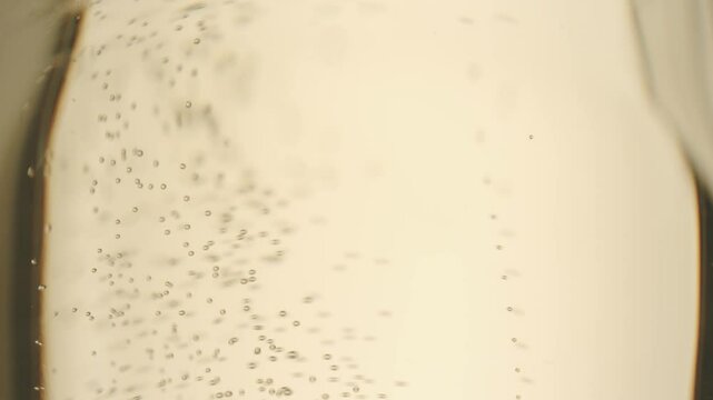 Anonymous person pouring champagne in glass. air bubbles in champagne glass. Low angle of unrecognizable person pouring fizzy champagne into elegant crystal glass against white background.