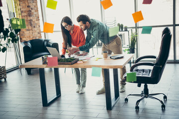 Two colleagues collaborate on a project in a modern office filled with ideas and creativity,...
