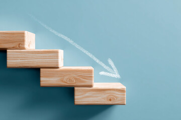 Wooden steps descending with a chalk arrow pointing down, set against a light-blue background, symbolizing decline or fall, suitable for business or financial concepts