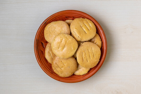 Delicious crispy Bakarkhani on clay plate on light wooden backdrop. Baqarkhani is a thick, spiced flatbread that is part of Mughlai cuisine. Top view.