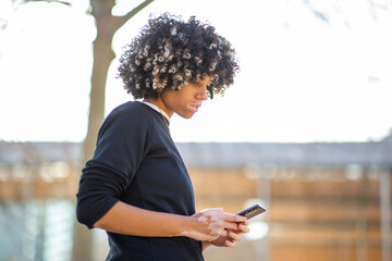 Young woman with vitiligo outdoors using smartphone with focused expression