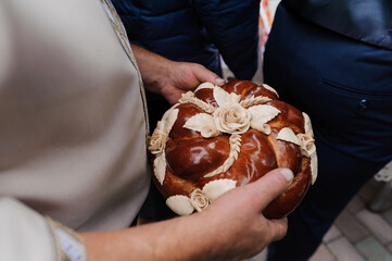 Traditional Polish wedding bread Korowaj decorated with wheat and roses held by a bride and groom...