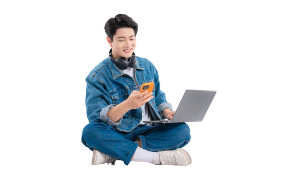 Full body image of Asian guy using laptop and phone on png background