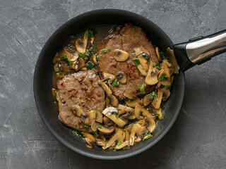 Delicious steak with sautéed mushrooms and fresh herbs in pan