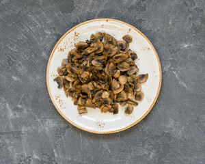 Top view of sautéed mushrooms on ceramic plate on slate background