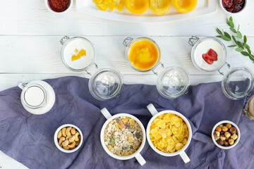 Healthy breakfast spread with cereal, granola, fresh fruits, and nuts on a white table