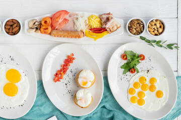 Delicious breakfast spread with eggs, bacon, nuts, and vegetables on white plates