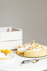 Lemon meringue pie with slice removed and yellow candle on minimalist table setting