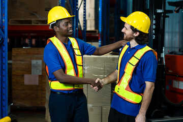 african warehouse worker shaking hands with caucasian colleague showing mutual respect and successful collaboration after completing packaging duty inside distribution center