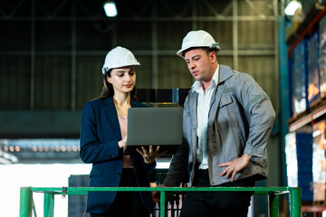 Caucasian adult female and male managers in safety helmets working together in warehouse analyzing...