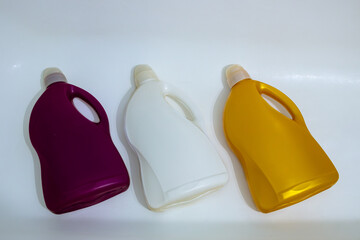 Three colorful plastic bottles of laundry detergent arranged in a row on a white background.