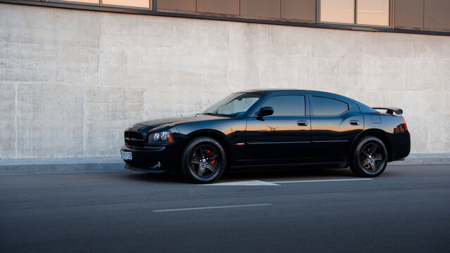 black Dodge Charger RT sedan in front of concrete wall. Side view of big american sedan with V8 engine. Kyiv, Ukraine - April 28 2016