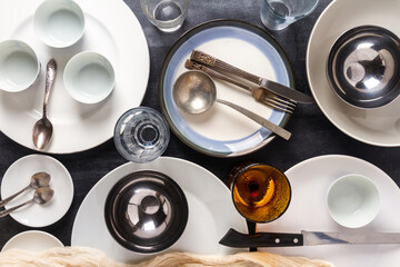 Top view of an empty plates, bowls, glasses and cutlery placed on a black chalkboard background. Flat lay. Top view. Food concept.