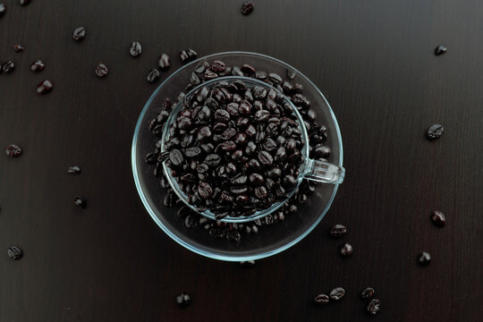 Coffee beans in clear cup on dark wooden table