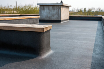 A contemporary flat roof showcases black EPDM material complemented by wooden edges
