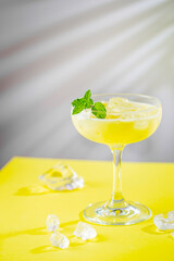 fresh banana and coconut tropical cocktail in a glass over yellow background