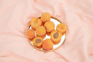 Apricot fruit on a mirror. Peach background. Summer aesthetic food concept.
