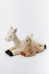 Baby alpaca stuffed animal sitting on a white background