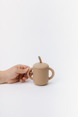 hand holding brown silicone sippy cup with straw