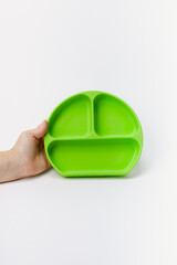 Hand holding green silicone plate for toddlers