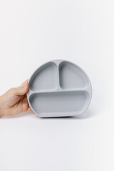 Hand holding grey silicone plate for toddlers