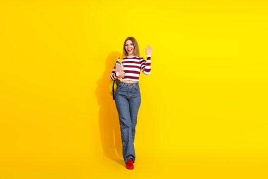 Charming young woman with a radiant smile wearing trendy casual clothes on a vibrant yellow background holding a notebook