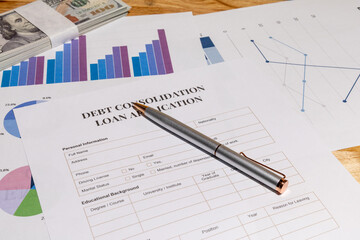A scene showing official debt consolidation loan application paperwork placed on a wooden desk with a stack of cash