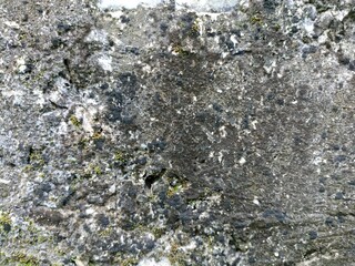 Weathered Stone Wall with Moss and Natural Erosion Texture. Close-up texture of a weathered stone...