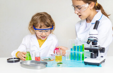 Laboratory examination of a child with test tubes, reagents and a microscope. Selective focus.