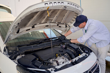 Mechanic performing maintenance on a white car in an indoor garage