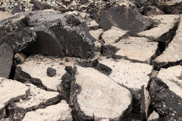 Asphalt broken into large pieces on the road. Repair work in the city. Road repair work. A mountain of removed asphalt pavement. Repair concept. A pile of asphalt debris close-up