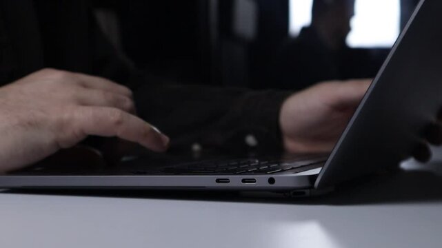An office worker uses a trackpad to flip through a mail cart while sitting at a laptop computer