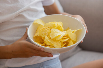 Close-Up of Hands Holding a Bowl of Potato Chips Indoors