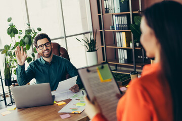 Smiling businessman greeting coworker in bright office workspace surrounded by plants and documents highlighting collaboration © deagreez