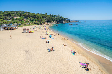 Tourists relaxing on sandy beach at costa brava in spain