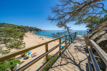Obraz premium Wooden walkway leading to sandy beach on costa brava, calonge, spain