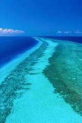 Seascape Vista: A breathtaking aerial view showcases the vibrant contrast of the deep ocean and shallow turquoise waters surrounding a secluded sandbar under a clear blue sky.