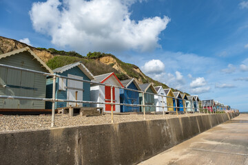 Colourful beach huts along the promenade in the seaside village of Overstrand on the North Norfolk...