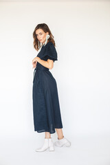 Attractive brunette woman wear navy blue dress with long cuffed puff sleeves and silver beads earrings. Sexy brunette woman with curly short hair look sensual.