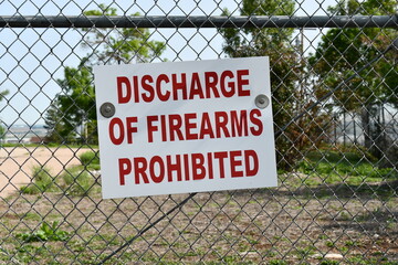 Chain link fence with bold sign. Discharge of Firearms Prohibited.