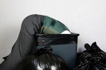 Businessman Stuffed in a Trash Can Surrounded by Piles of Garbage Bags. Over a Barrel. Concept of Being Sacked or Fired.
