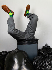 Businessman Stuffed into a Trash Can Wearing Argyle Socks. Over a Barrel. Concept of Being Sacked or Fired or Being Unfashionable.