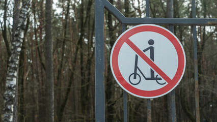 A sign on the park gate prohibits scooter entry. Clear rules for park visitors to ensure safety and...