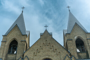 Fototapeta premium The image of St. Anne's Neo-Gothic Church in Rakow, Belarus, showcases spring's beauty with its Gothic and Classicism elements, adorned with Catholic crosses, symbolizing faith and heritage.
